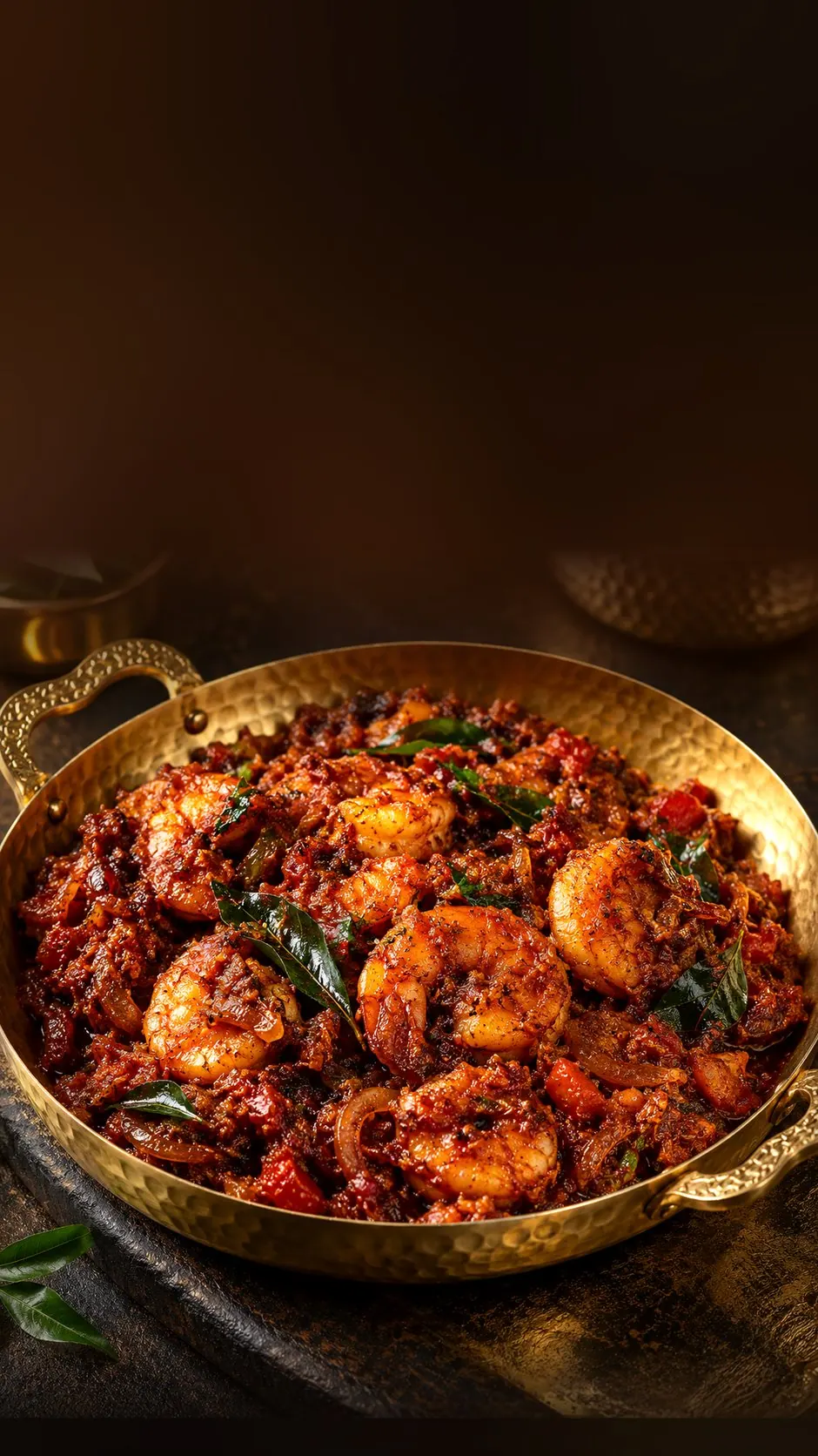 Spicy prawn masala with curry leaves in a brass serving dish
